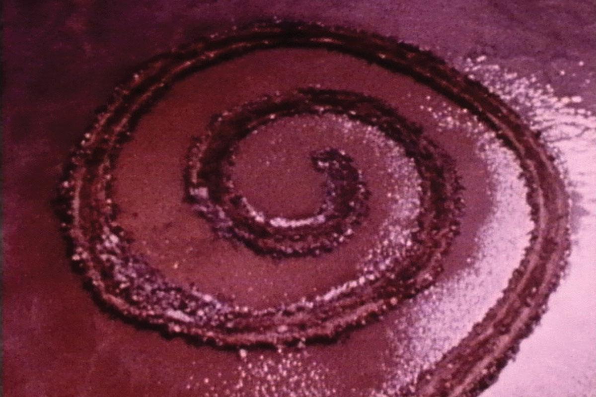 aerial view of red water with a large spiraling jetty in the center
