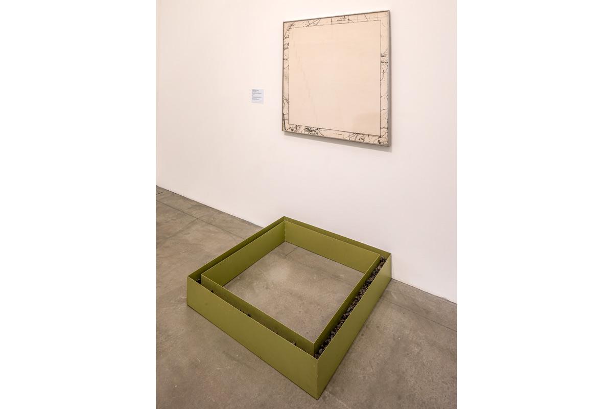 a square metal sculpture on the wall next to a square map of the same size displayed on the wall
