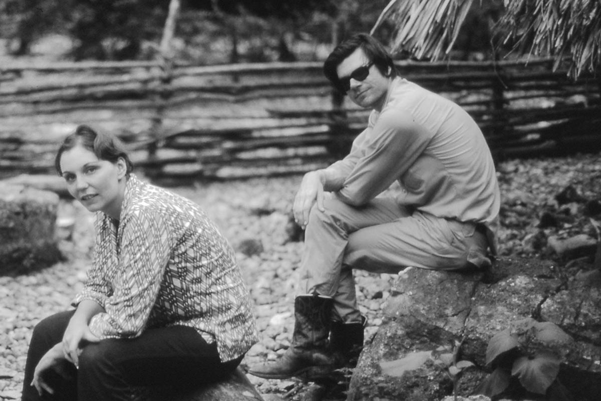 black and white image of two figures seated on rocks looking at the camera