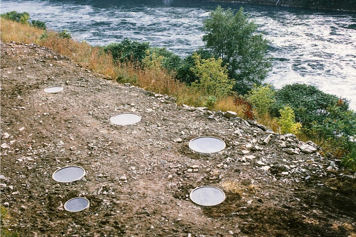 six circular pools of water on the shore alongside a river