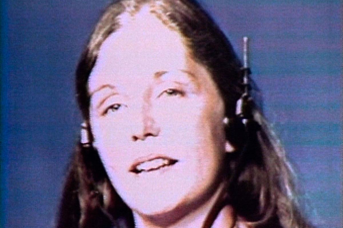 Nancy Holt looking toward the camera with her mouth open and headphone on