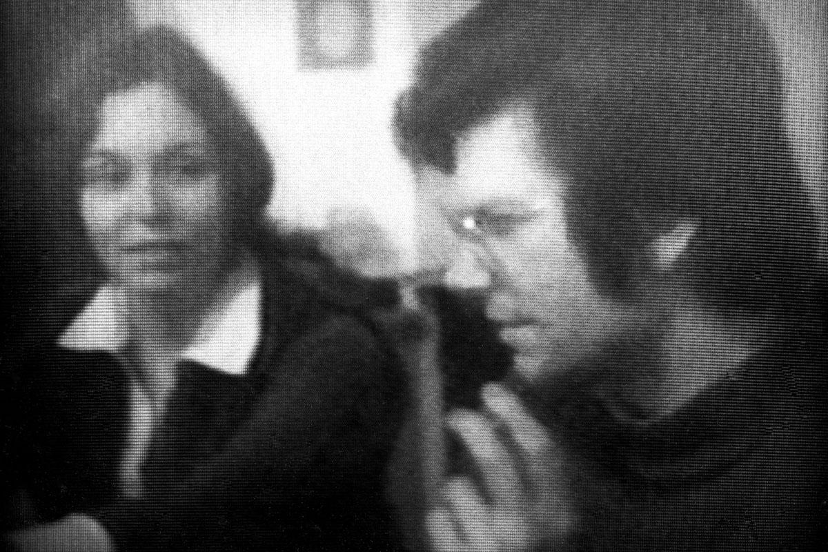 Black and white, a young woman and man seated next to each other in conversation.