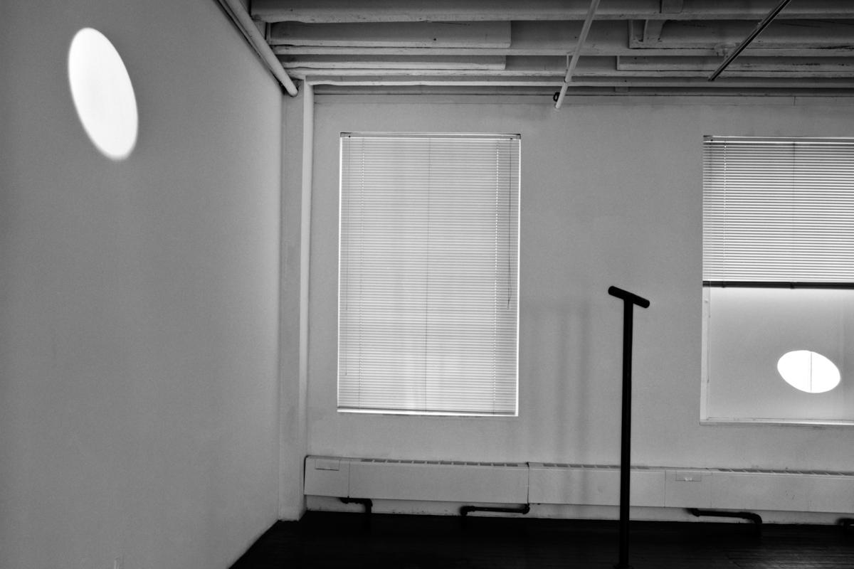 a room with an ellipse of light on a wall on the left, a locator in the middle, and a cutout in a window on the right