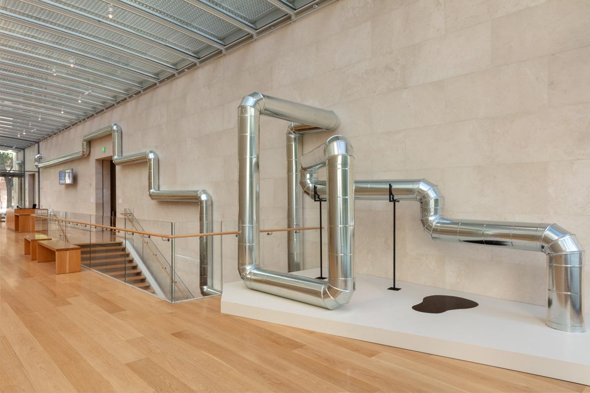 A steel pipeline weaving through an exhibition space