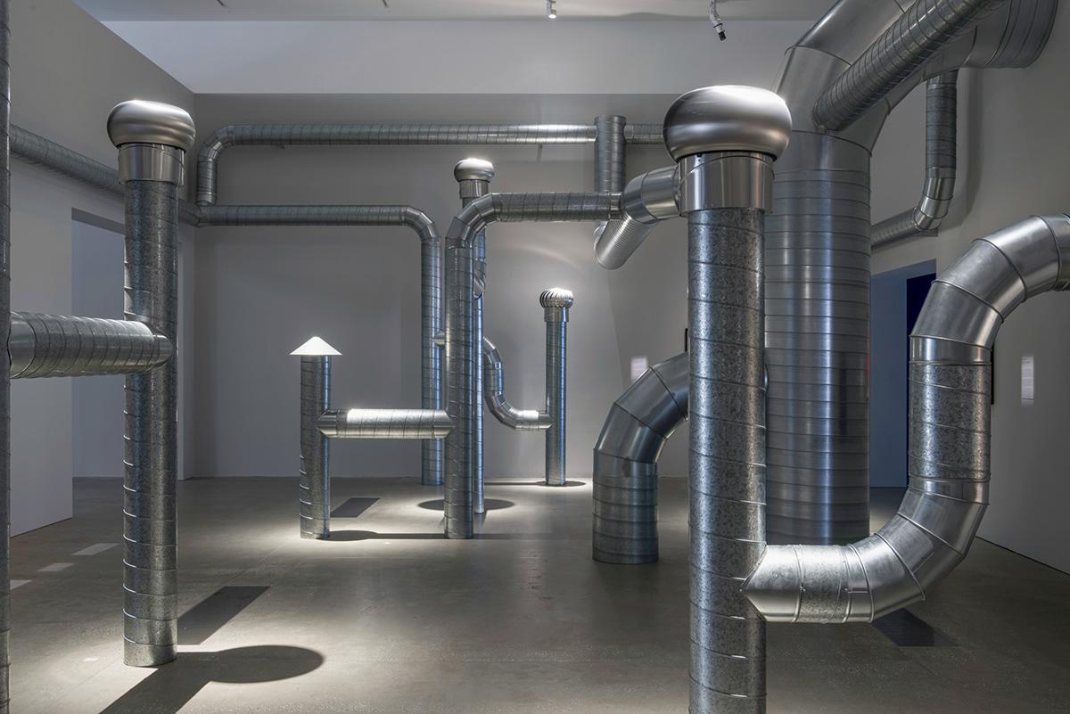 a network of steel ventilation ducting installed in a white walled room