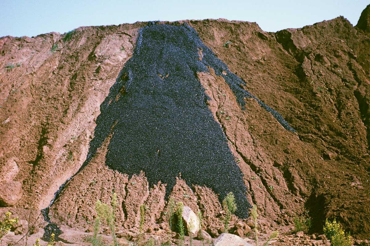 an earthen hillside with a large expanse of asphalt running down the center