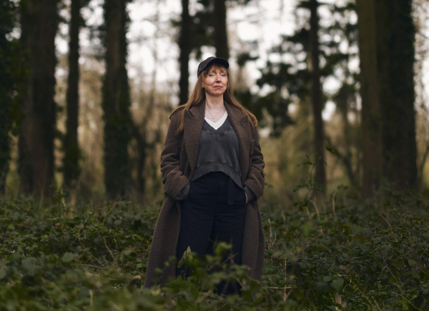 Susan Philipsz standing in a wooded area