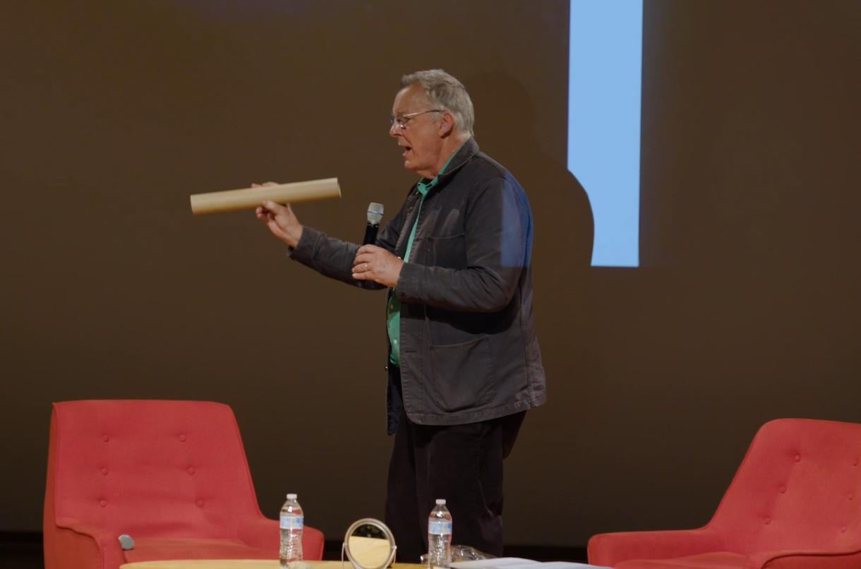 an artist talking with a paper tube