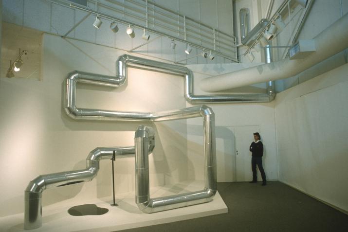 steel duct zig zags through the air and along walls in a white gallery space