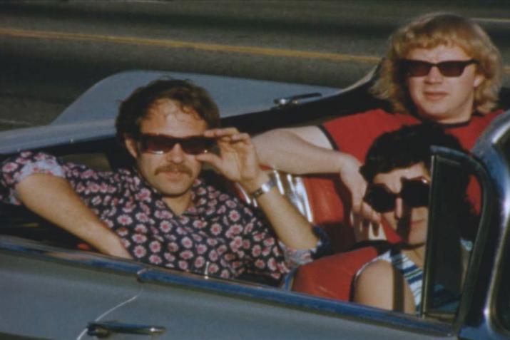 three people wearing sunglasses sitting in a convertible car
