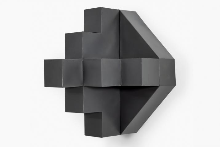 a geometric gray sculpture on a white wall