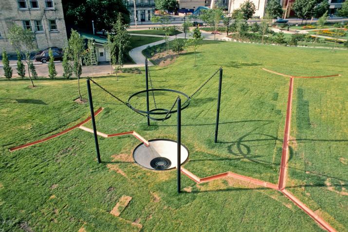 aerial view of a park with large sculpture made of clay pipes and a large central drain.