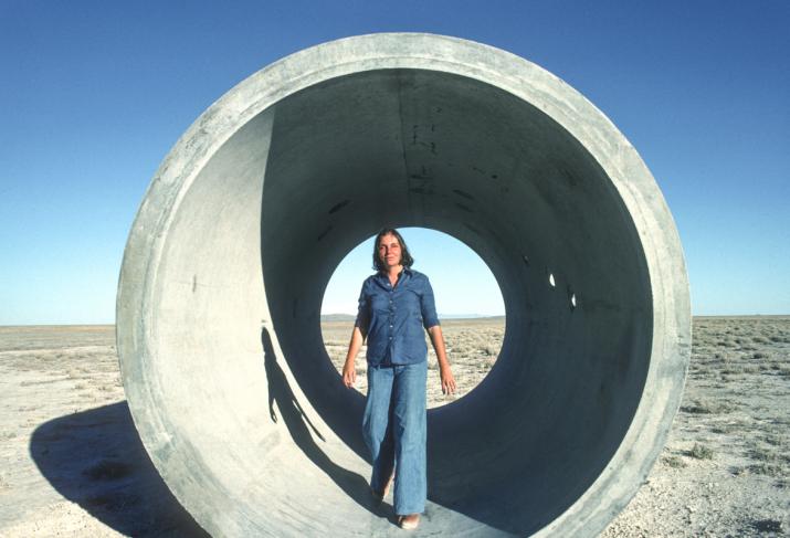 Nancy Holt standing inside one of the Sun Tunnels, a large concrete cylinder in the desert