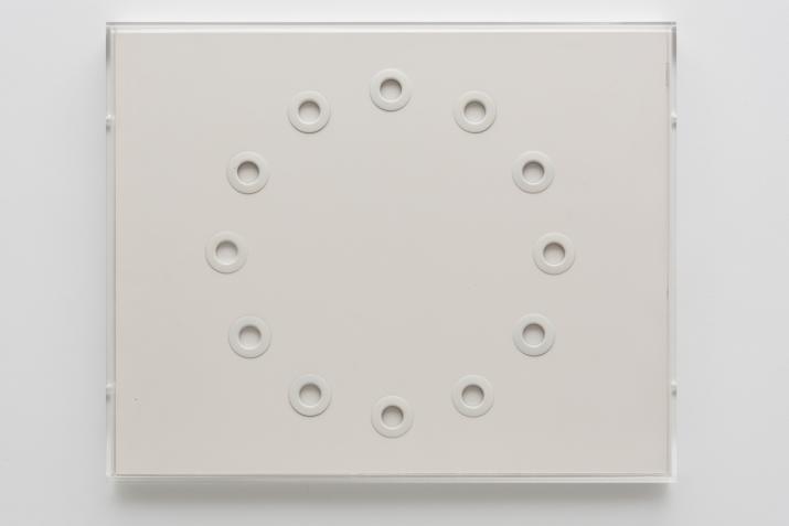 Circular white grommets arranged in a circle on white foamcore