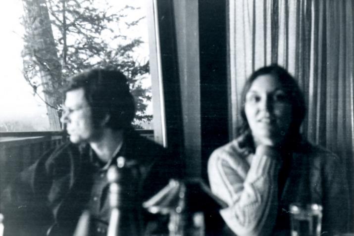 two figures sitting next to a window
