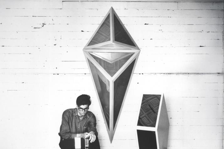 Robert Smithson in his studio with two mirrored geometric sculptures surrounding him