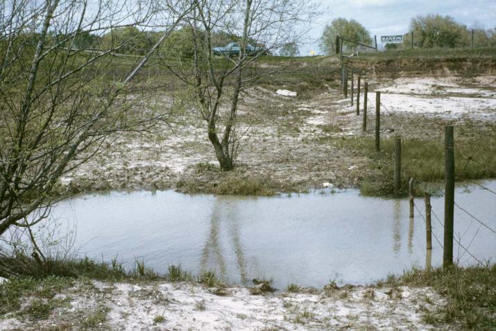 a flooded drainage bisected by a barbed wire fence