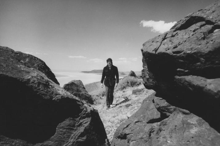 Robert Smithson walking between large boulders on the shore of the Great Salt Lake