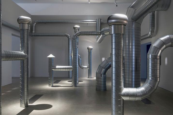 a network of steel ventilation ducting installed in a white walled room