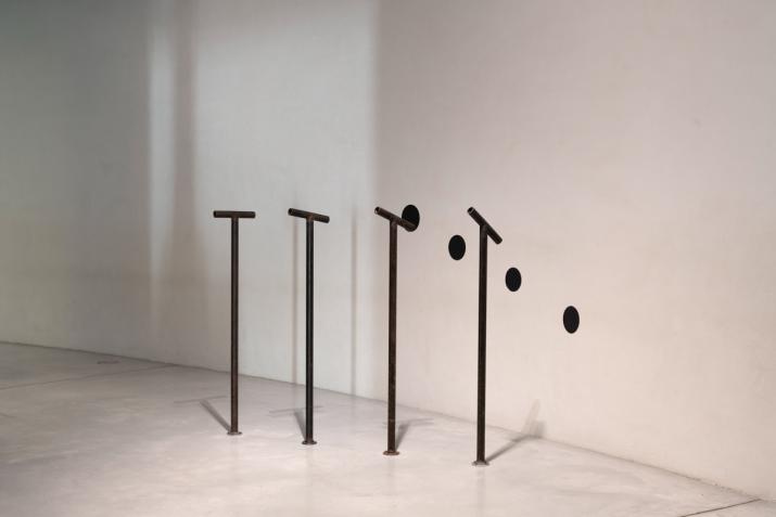 four steel pipes extending up from the floor with four viewing pipes pointed at four black painted circles on the wall