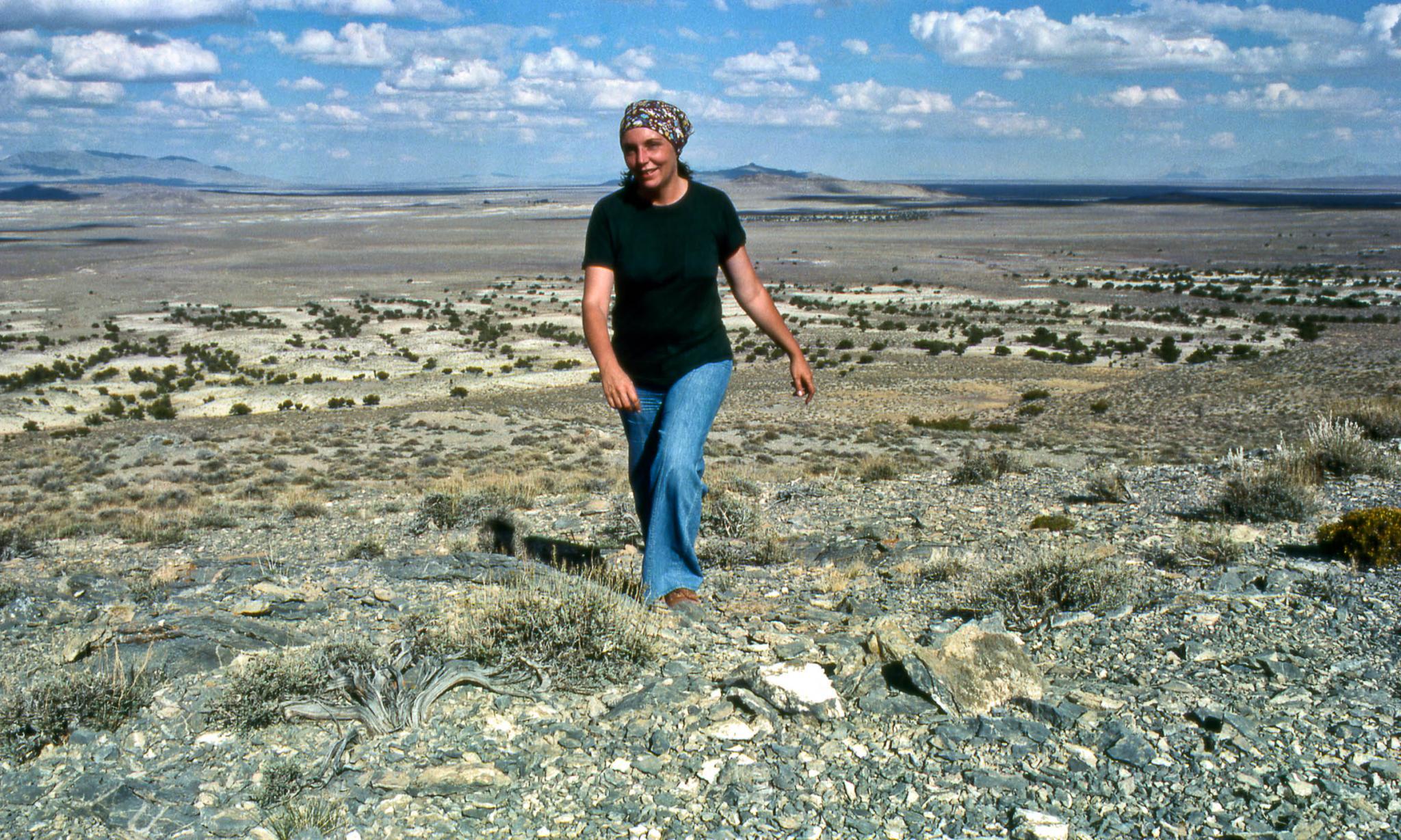 Nancy Holt walking uphill surrounded by a landscape view of the Utah vista.