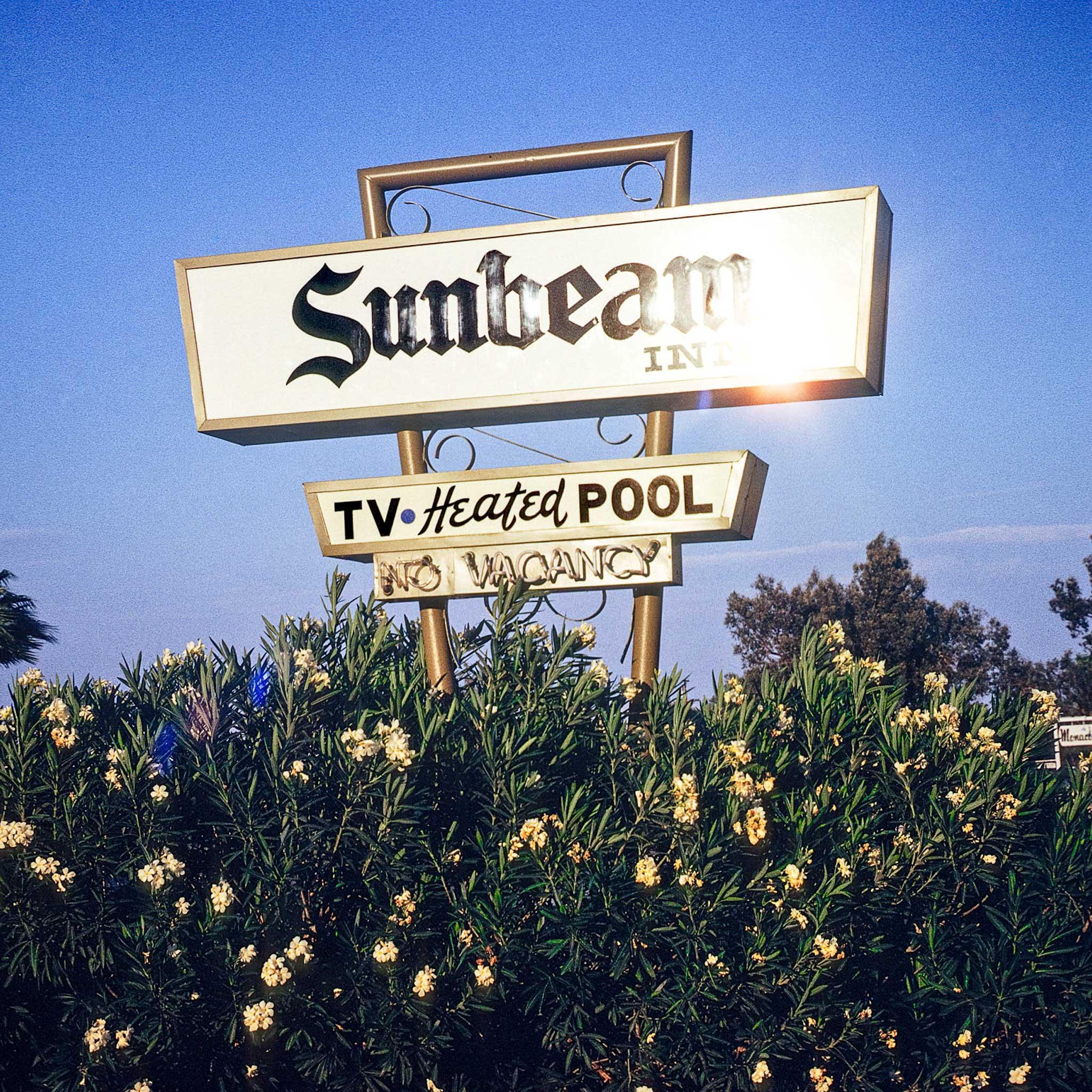 A sign that says "sunbeam" above a flower bush