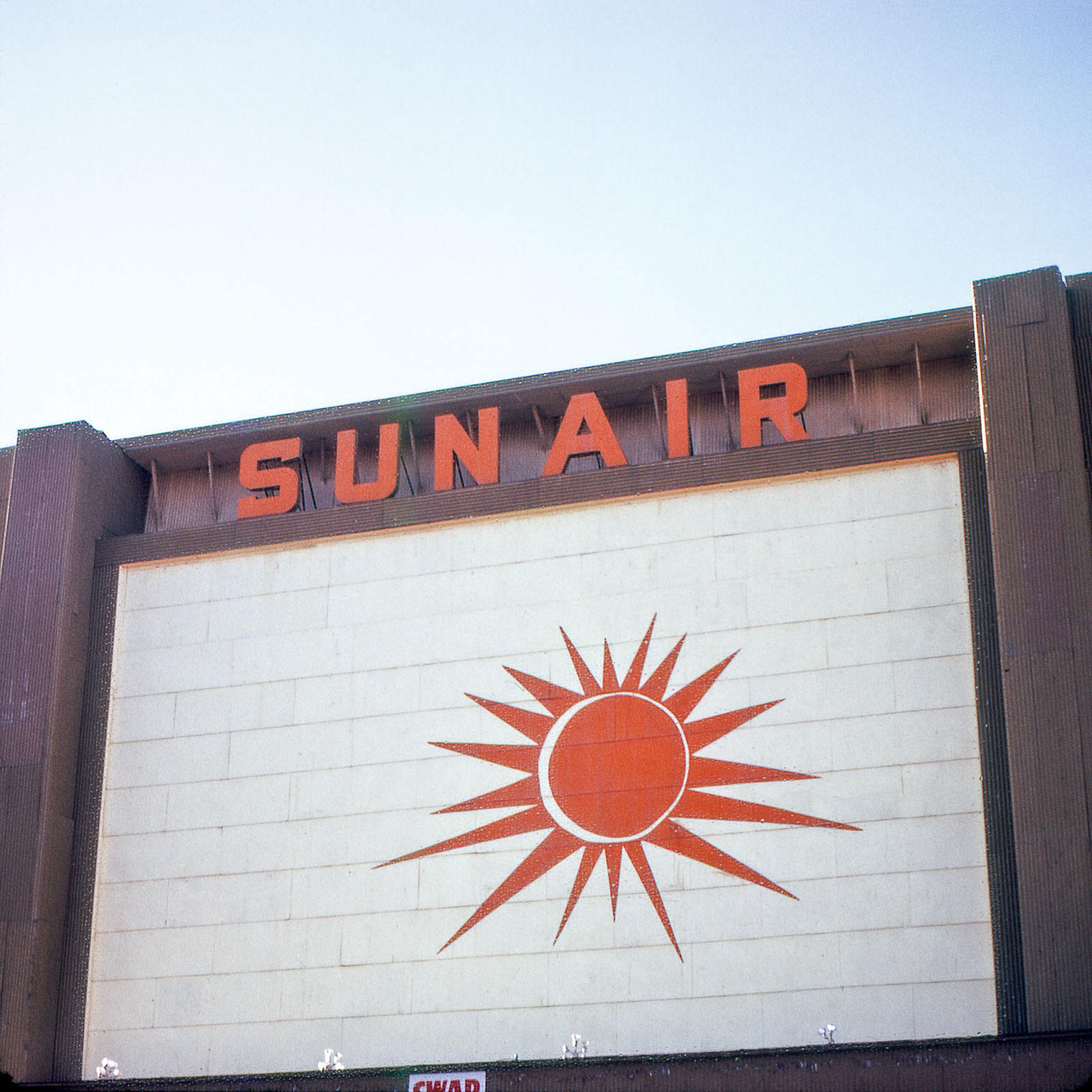 A sign that says "SunAir" and has a red sun graphic