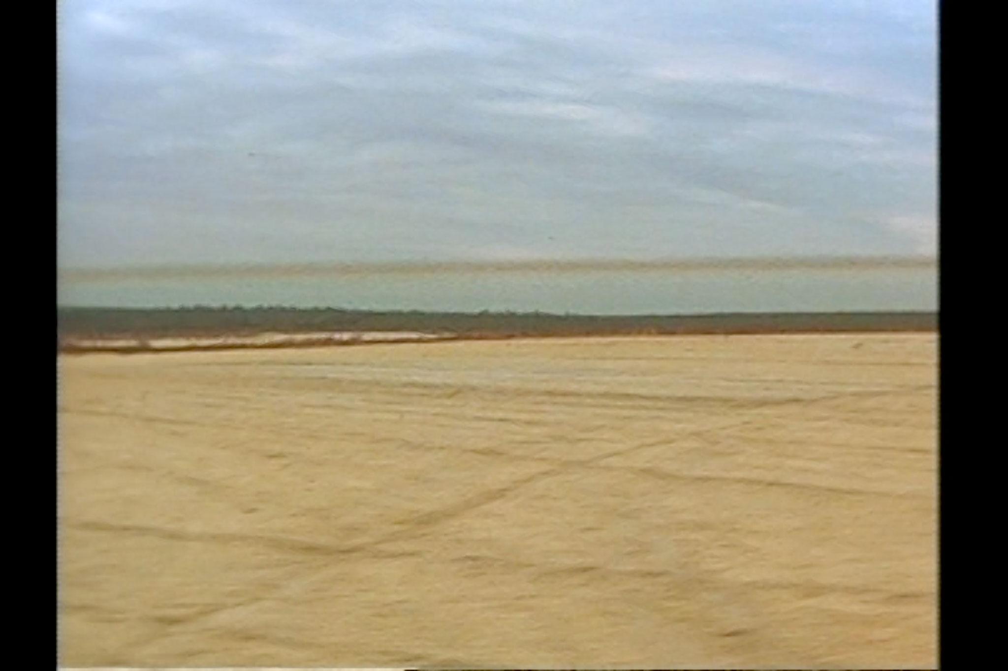 a barren landscape with water in the distance