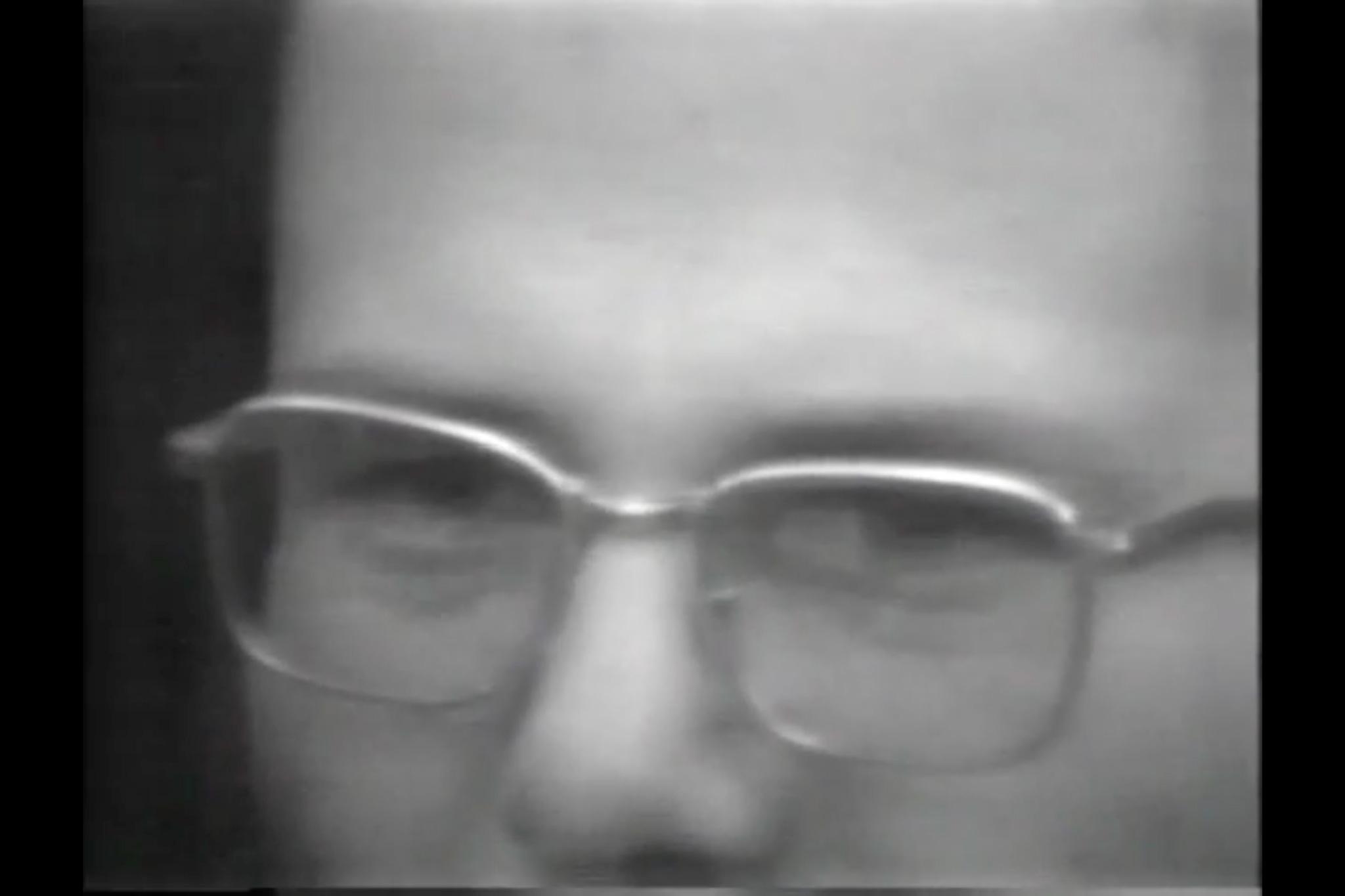 Black and white close-up image of a man with glasses.