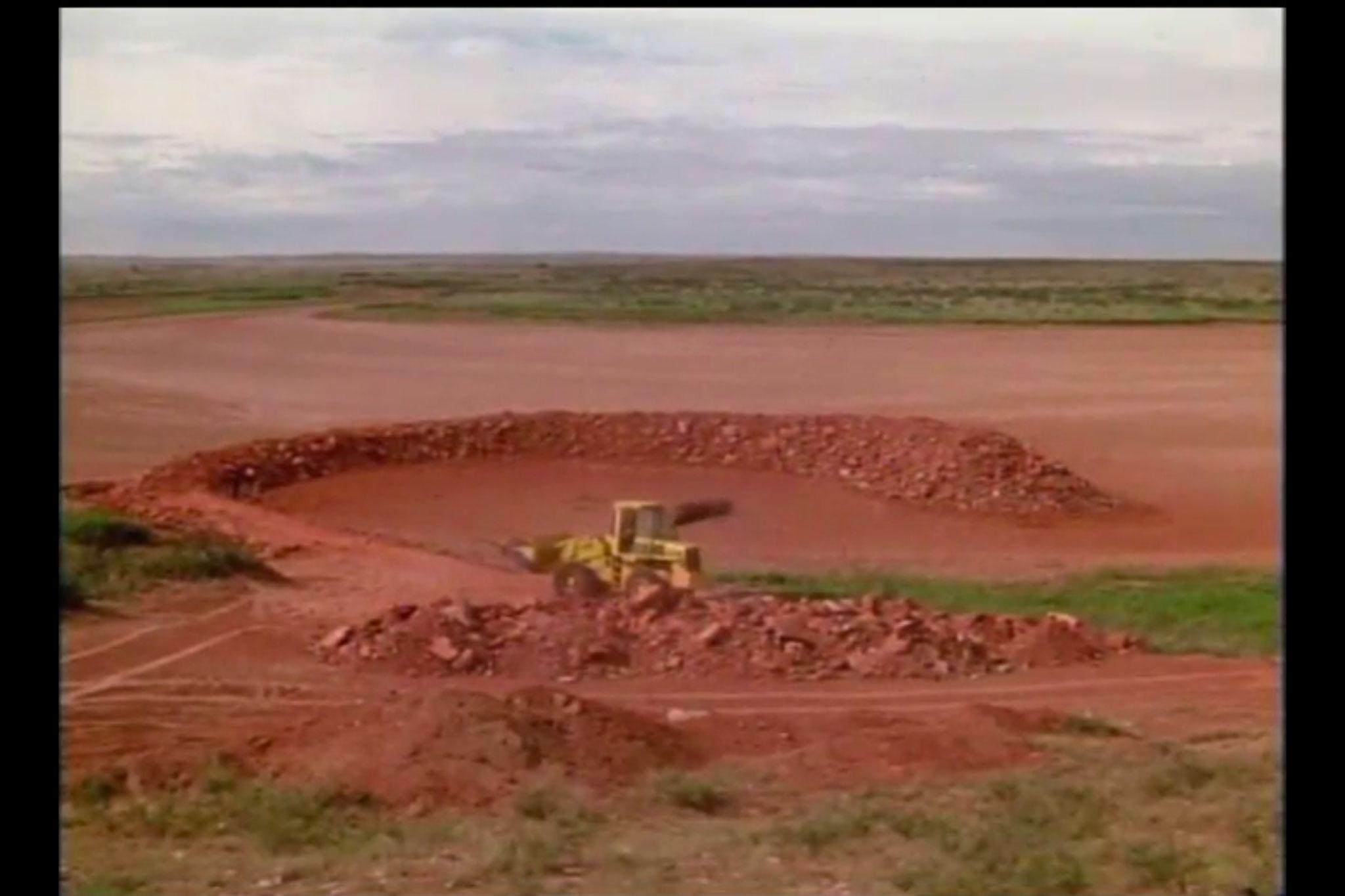 a circular ramp made of earth, emerging out of a dry lakebed