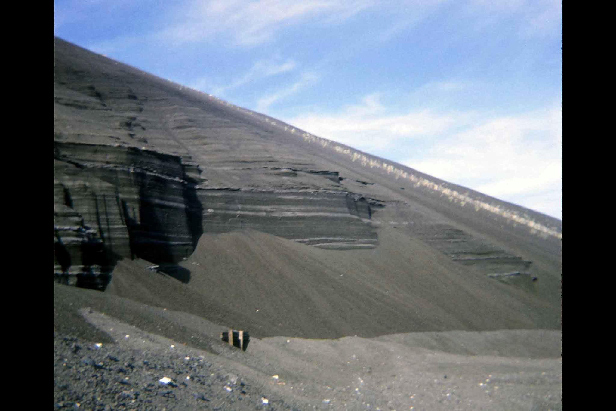 A steep slope of rock and gravel with blue sky in the background