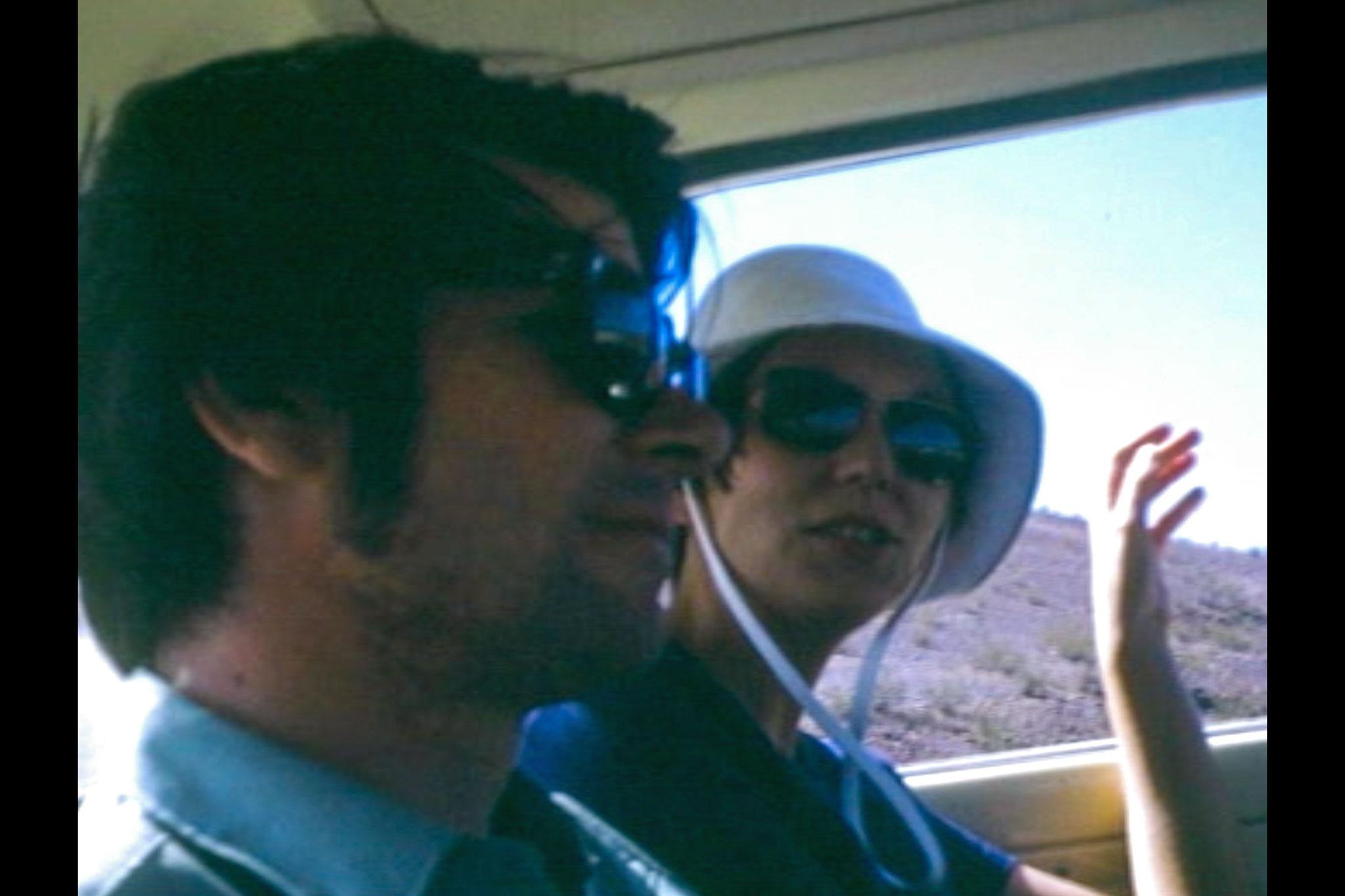 A young man and woman riding side by side in the backseat of a car.