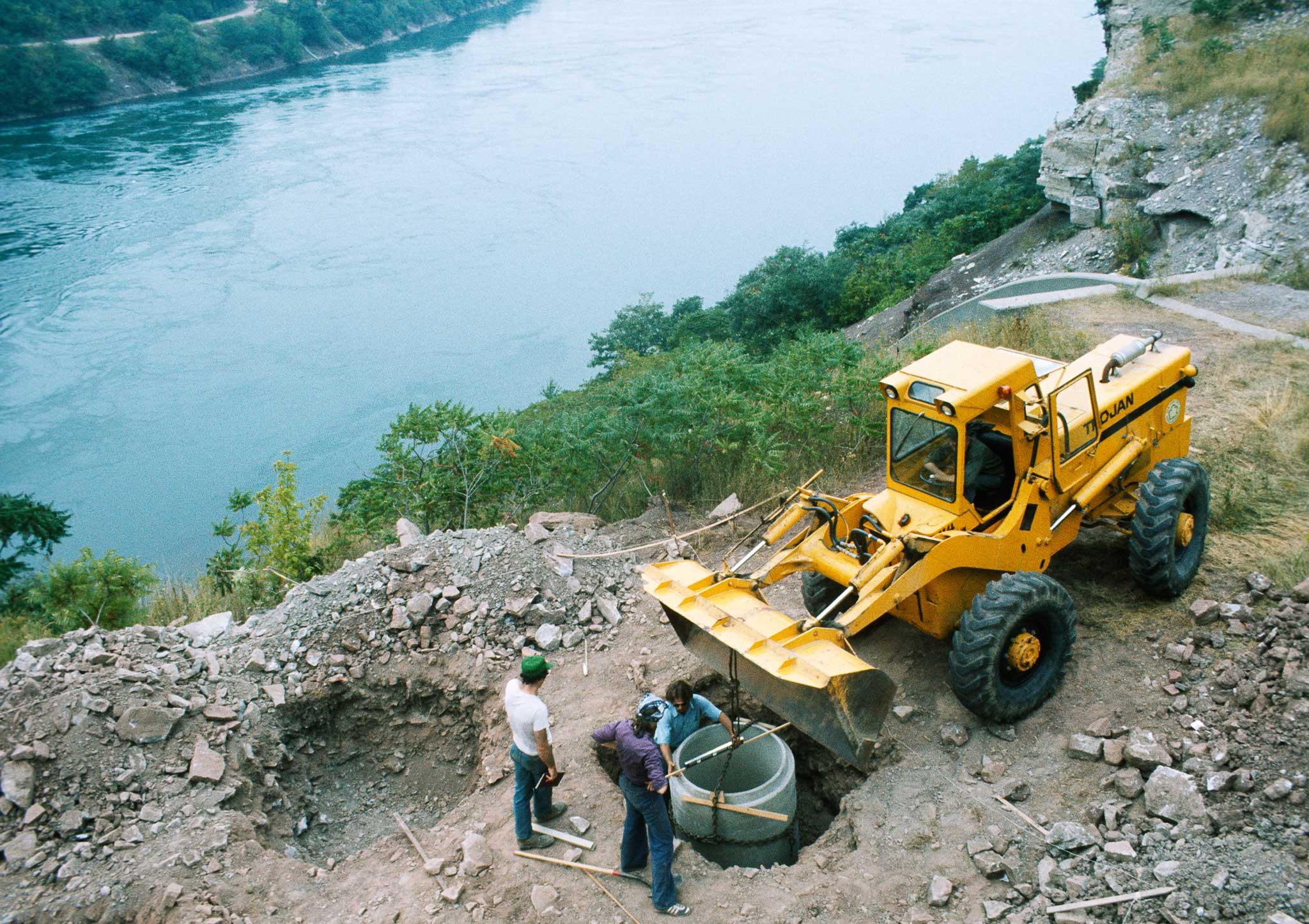 A construction site with a large yellow bulldozer next to a river.