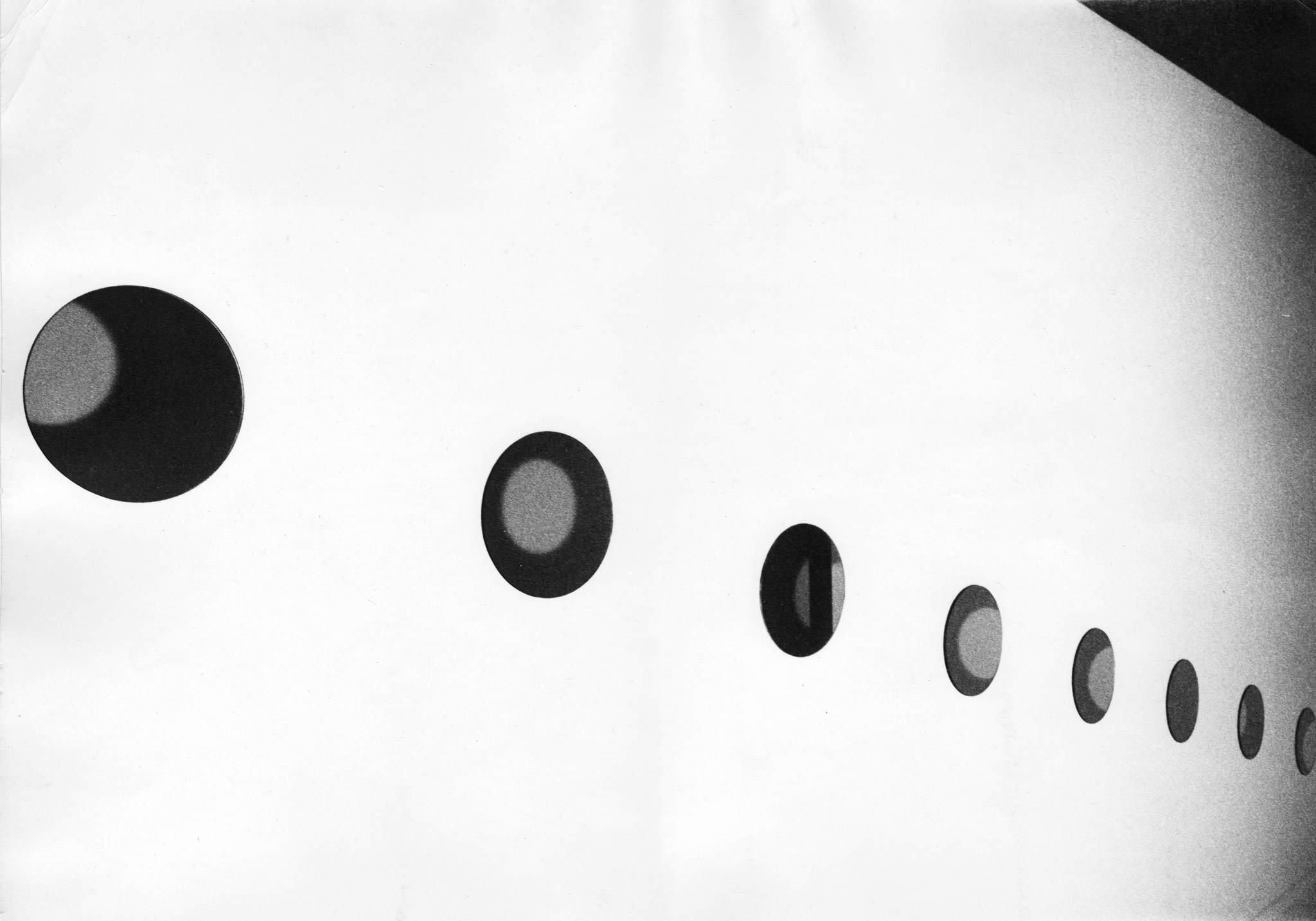a line of circular mirrors spaced out and mounted on white wall