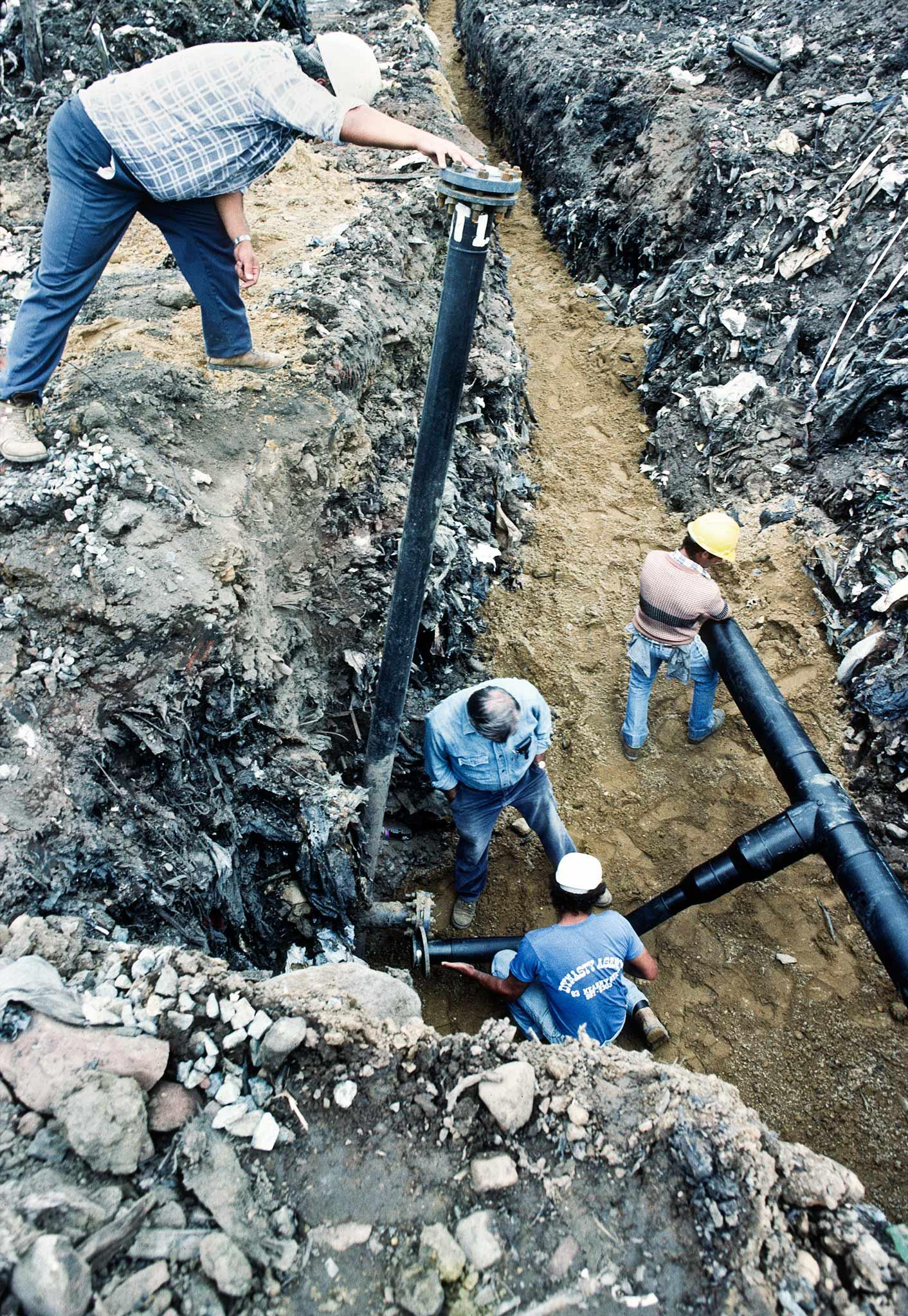 Workers installing methane pipes in a trench