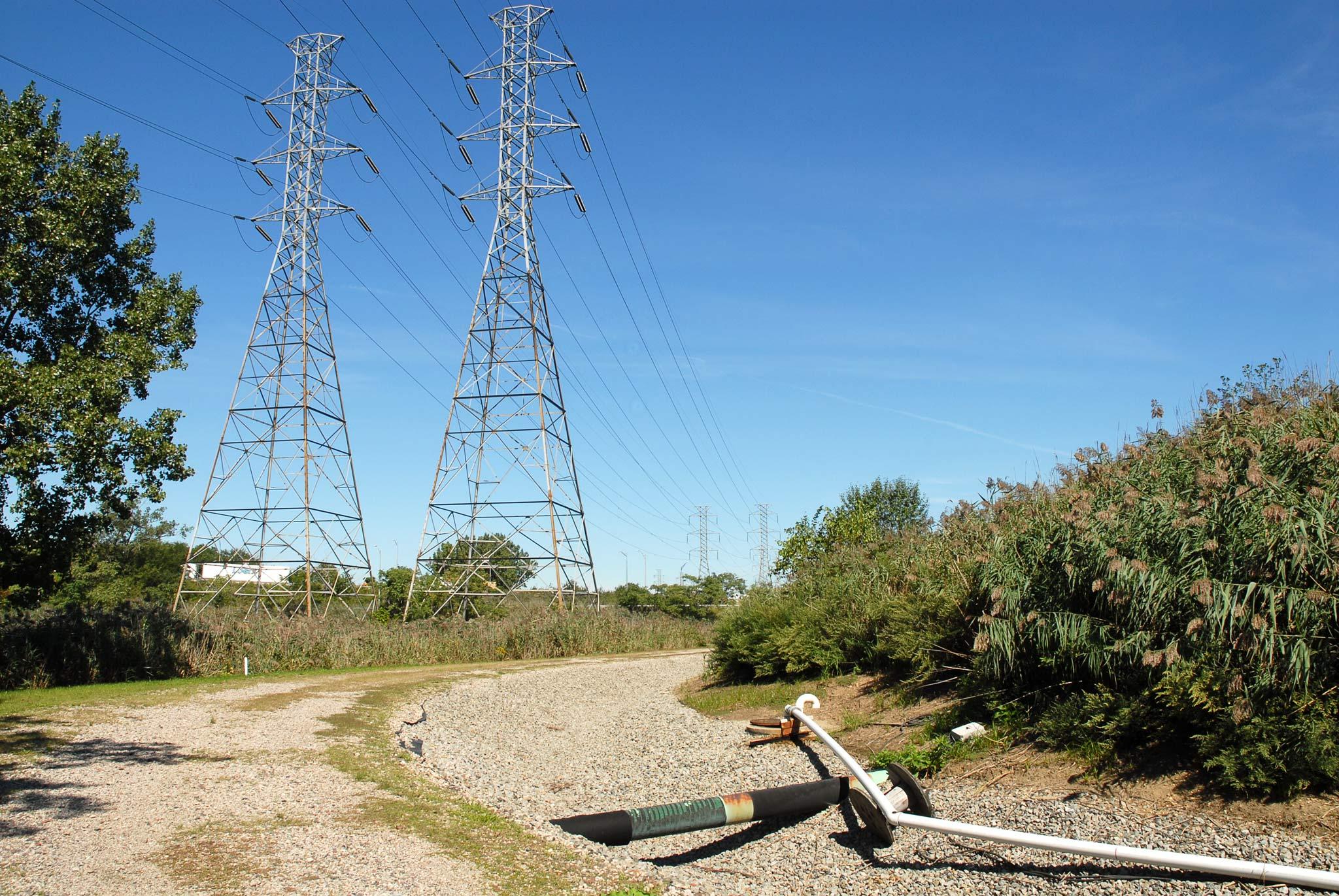 A gravel road with two tall electricity towers in the background
