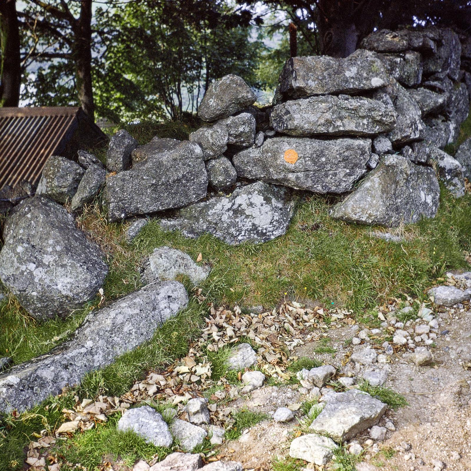 a pile of stones with a small orange circle painted on large rock near the center of the image