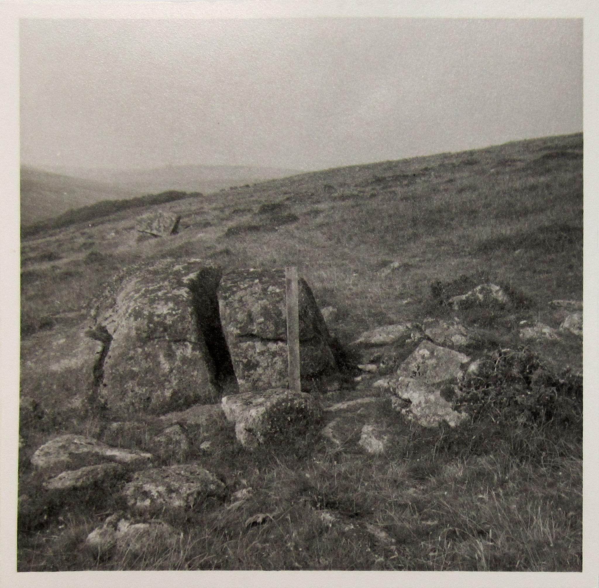 black and white image of a large boulder in the foreground and rolling hills in the background