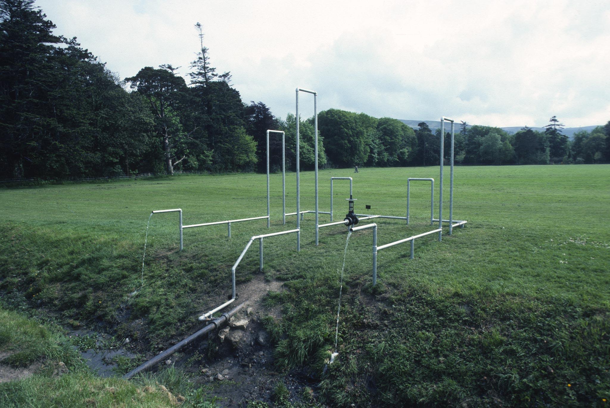 galvanzied pipes organized into rectilinear structures in a field outside a large home in Ireland
