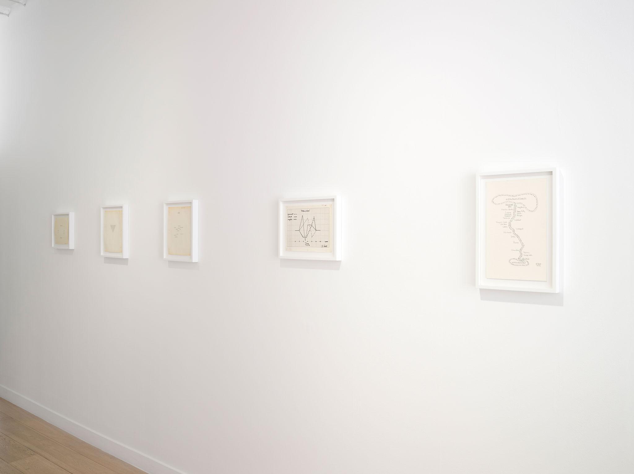 framed works on paper hung in a line on a white wall