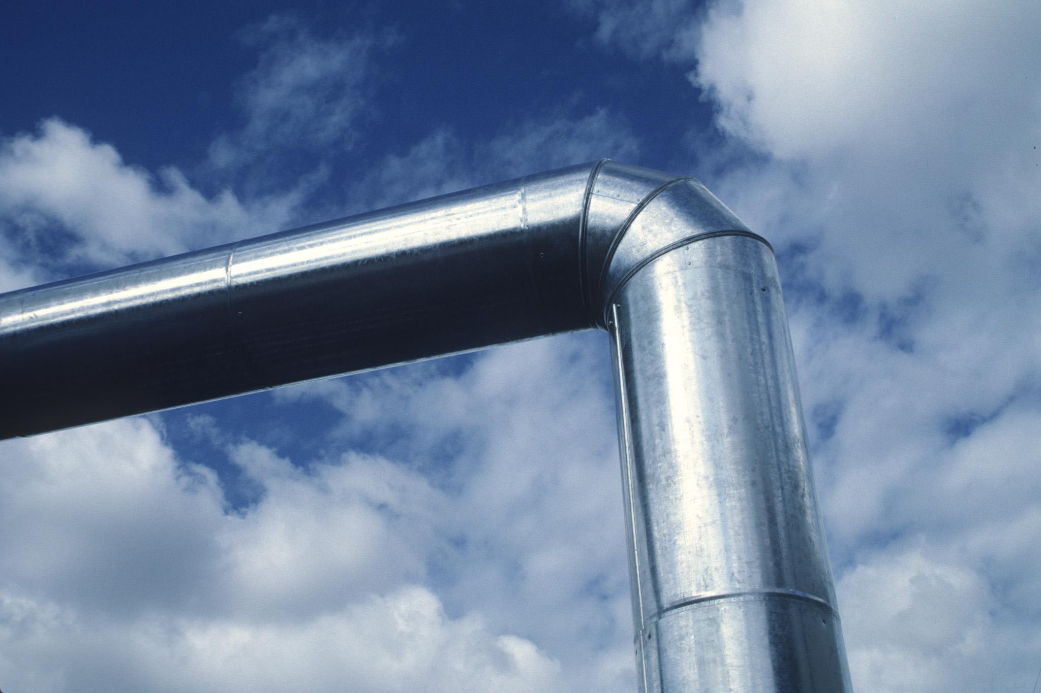 detail image of a large steel duct against a blue and white sky