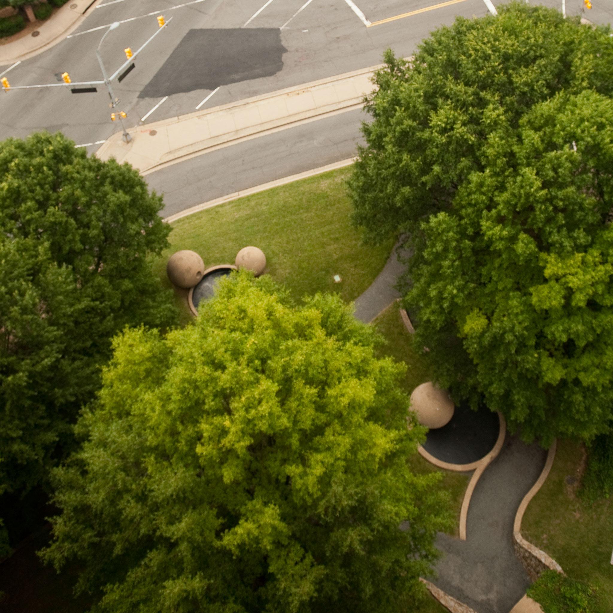 aerial view of trees and large spheres of concrete near a road