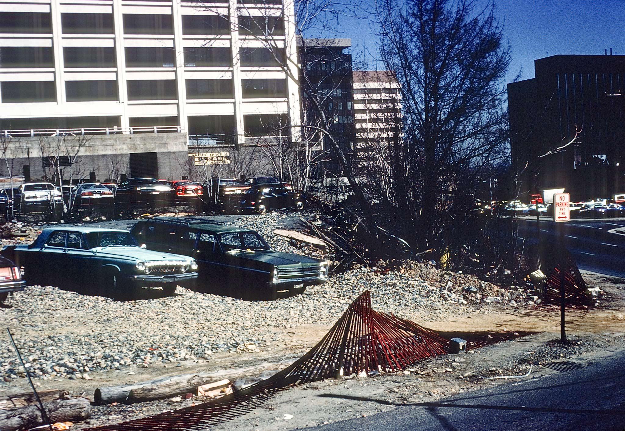 several cars in a gravel parking lot with a building behind