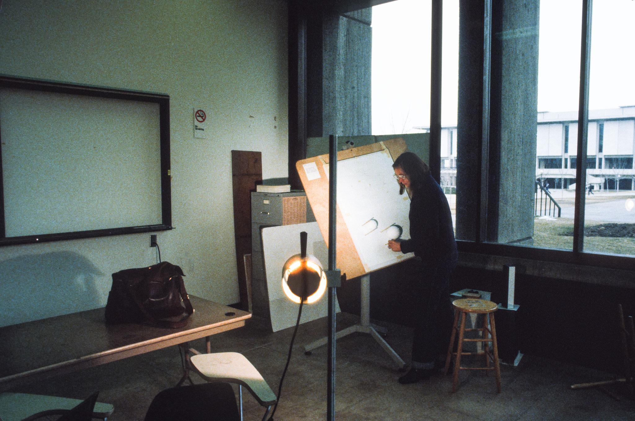 a person working on a small model on an easel with a light pointing directly at the model