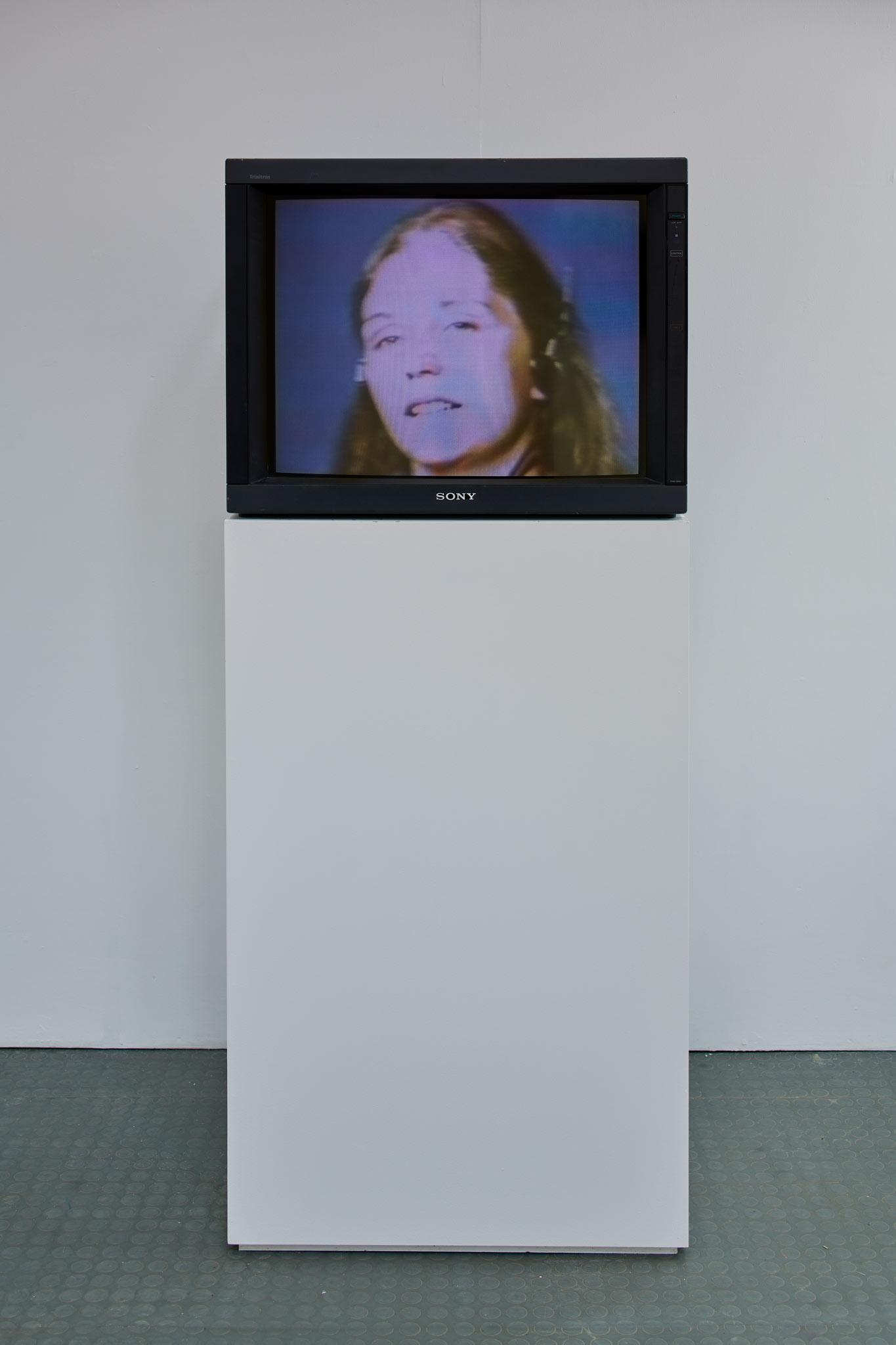 a monitor displaying a woman's face on a pedastal