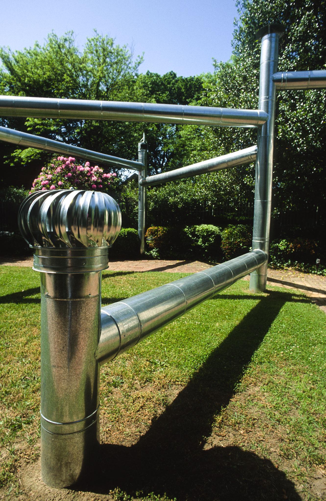 outdoor sculpture made of spans of steel duct that come out of the ground and span stretches