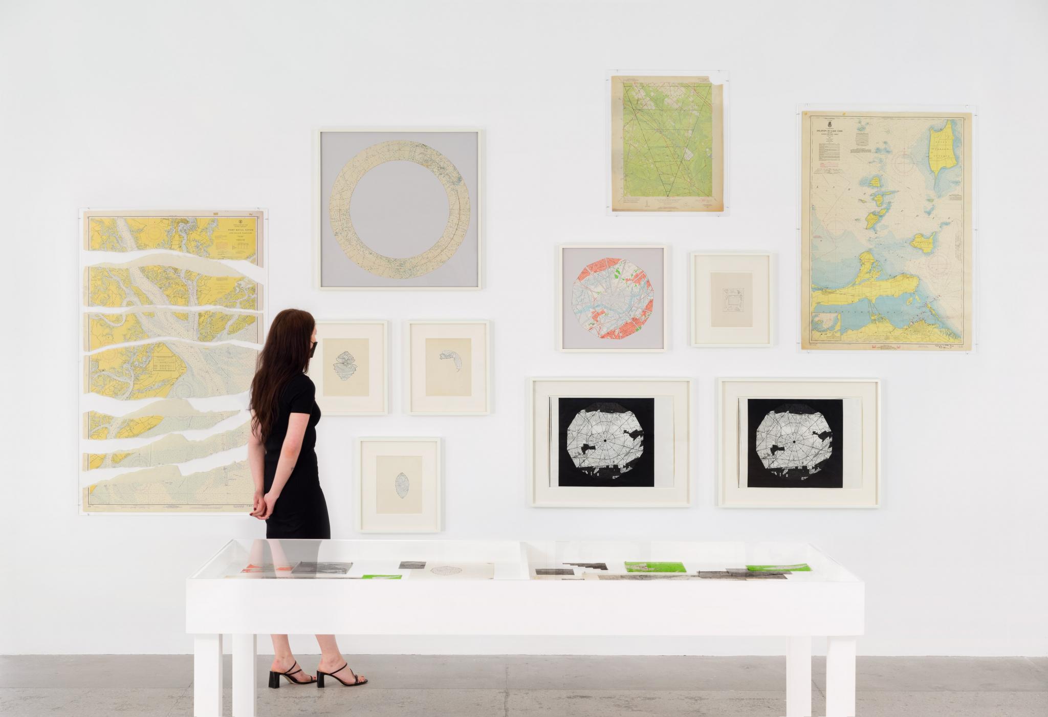 Person looking at Robert Smithson map artworks on a wall