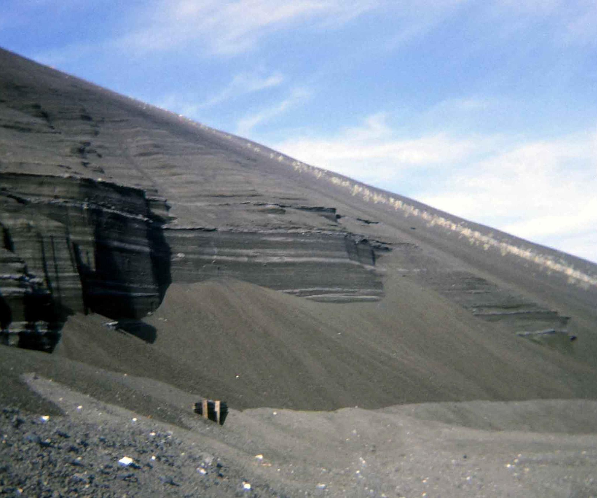 A steep slope of rock and gravel with blue sky in the background