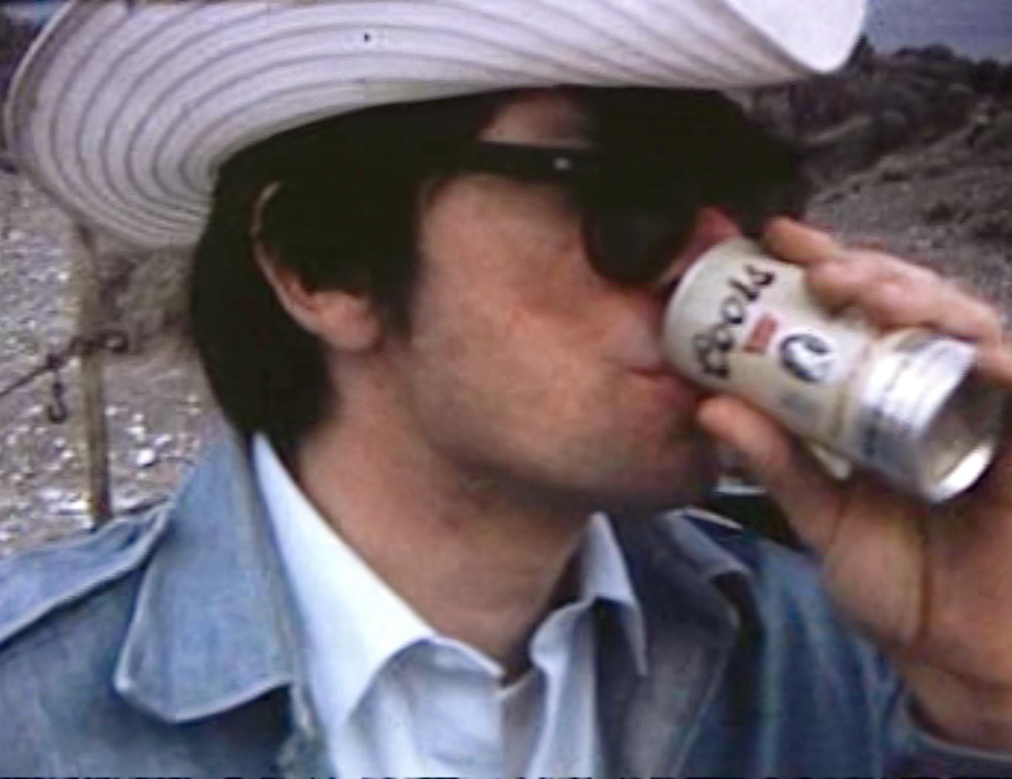 A man wearing a cowboy hat drinking a Coors beer