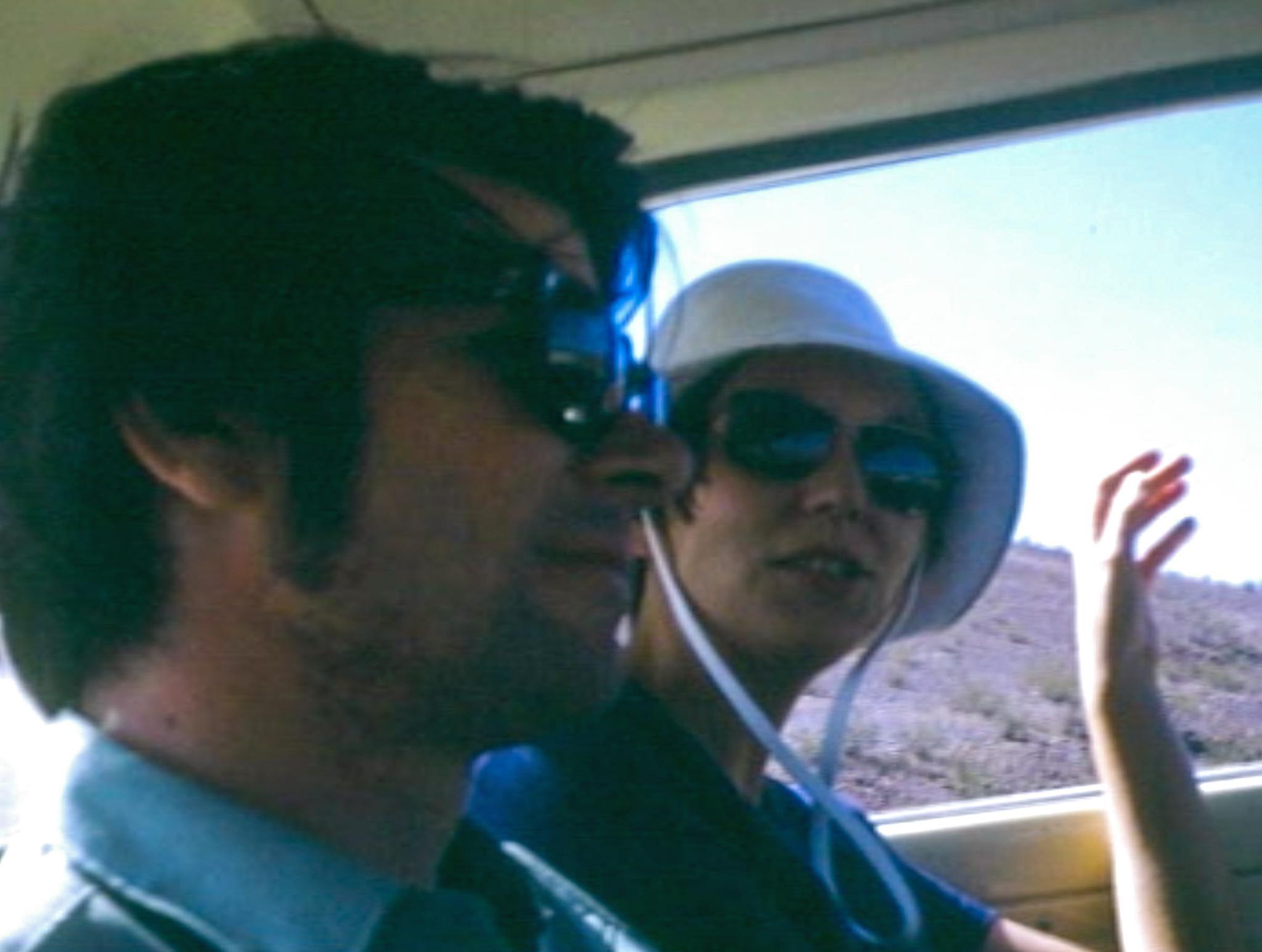 A young man and woman riding side by side in the backseat of a car.